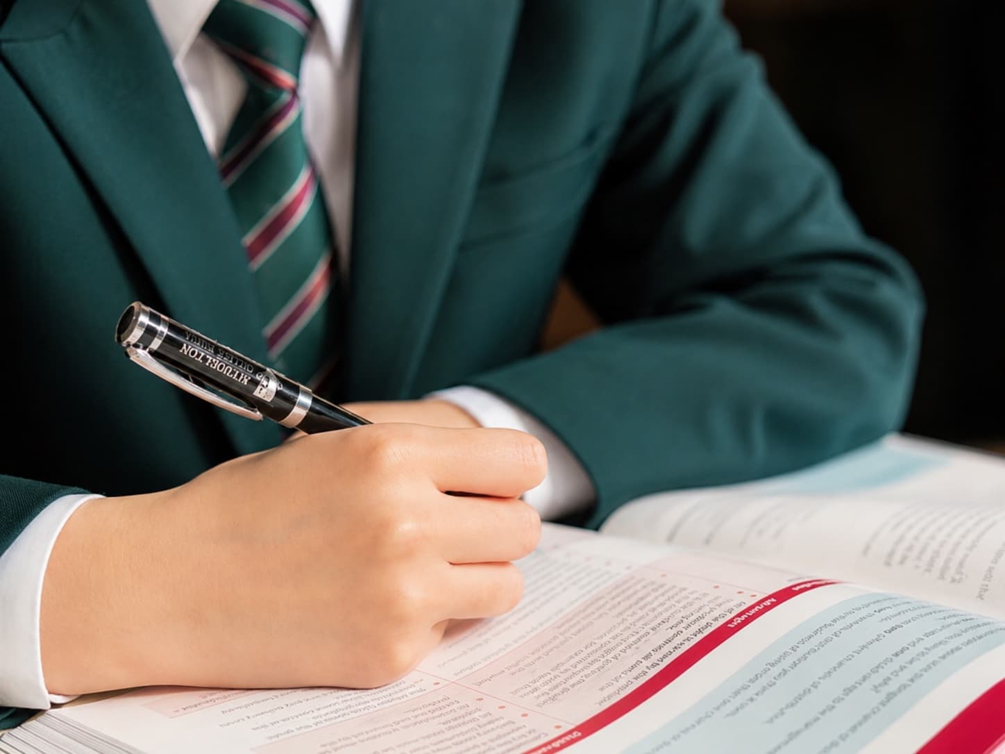 学生填写入学评估材料:手持钢笔在课本上书写